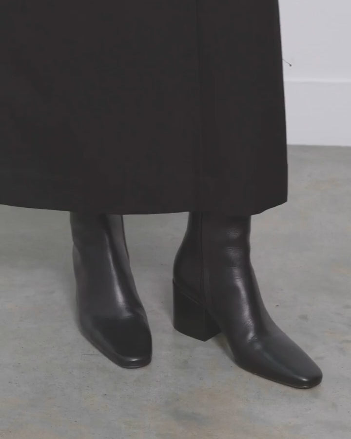 Model walking in Dear Frances Alma Ankle Boots in black leather, showing the square toe and block heel